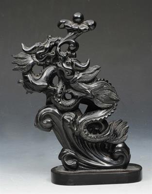 Lot 91 - A SOUTH EAST ASIAN CARVED BLACKSTONE STYLISTIC MODEL of a dragon with lotus leaves