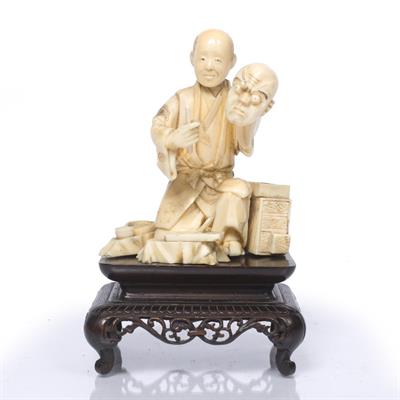 Lot 943 - A Japanese ivory okimono of semi-kneeling antisam holding a noh mask and a tool