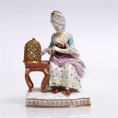 Lot 322 - A Meissen porcelain model of a girl feeding a bird in a cage