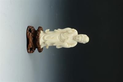 Lot 122 - A JAPANESE CARVED IVORY OKIMONO of a female subject holding a scroll on a carved hardwood stand