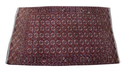 Lot 194 - AN OLD TEKKE TURKOMAN BRICK RED GROUND MAIN CARPET decorated six rows of fourteen guls within a pane