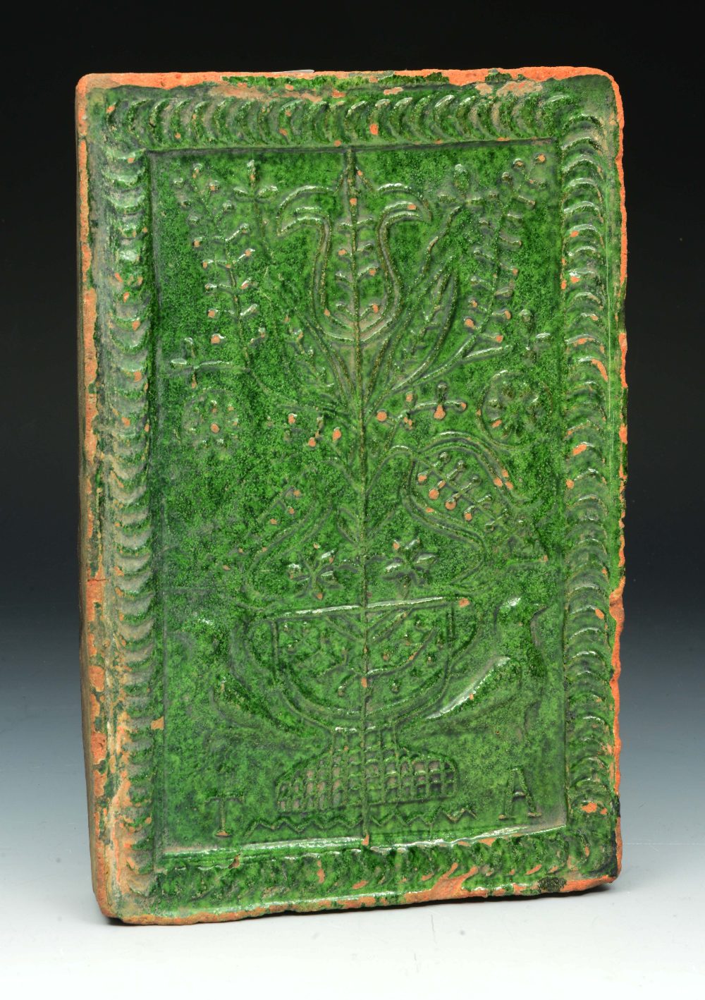 Lot 337 - A 17TH CENTURY ENGLISH GREEN SLIPWARE MARRIAGE STOVE TILE decorated with a central tulip and two bir