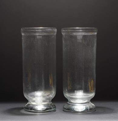 Lot 256 - A PAIR OF CYLINDRICAL GLASS HURRICANE LAMPS with candle holders within and circular bulbous bases wi