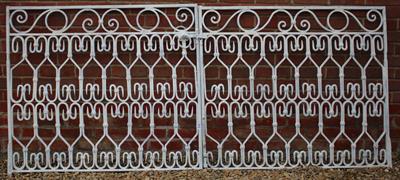 Lot 604 - A PAIR OF WHITE PAINTED WROUGHT IRON GATES with repeating scrolled decoration