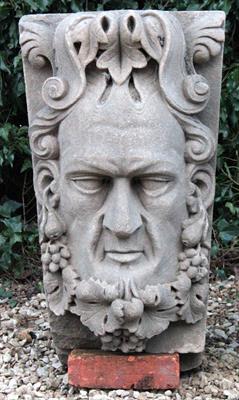 Lot 620 - A LARGE CARVED SANDSTONE KEY STONE with mask of a man with trailing vine entwined beard 42cm wide x