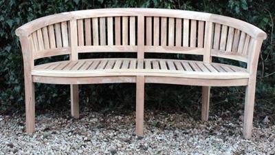 Lot 630 - A TEAK GARDEN BENCH of curved form with a slatted back and seat and square legs 156cm wide