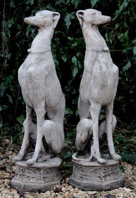 Lot 669 - A PAIR OF CAST COMPOSITE STONE SCULPTURES in the form of seated whippets each on an octagonal base 8