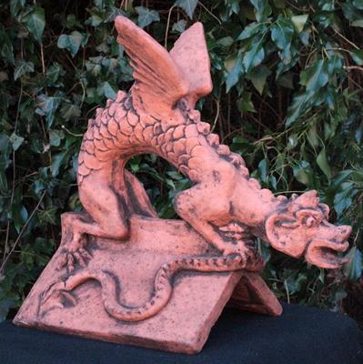 Lot 680 - A CAST TERRACOTTA DRAGON ROOF RIDGE FINIAL of a dragon crouching on a triangular ridge tile 51cm lon