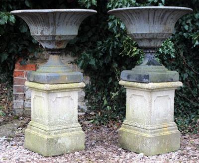 Lot 689 - A PAIR OF OLD BLACK PAINTED CAST IRON URNS of a shallow campana form with fluted bodies