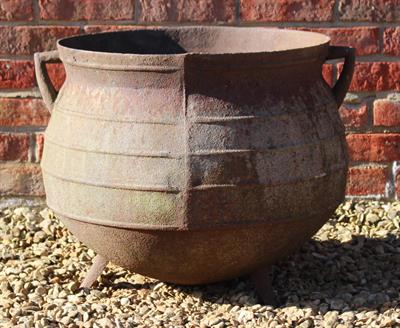 Lot 742 - AN OLD CAST IRON CAULDRON with twin angled handles and three feet and ribbed to the side (cracked to