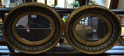 Lot 87 - A pair of gilt and ebonised oval wall mirrors