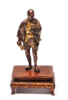 Lot 81 - A JAPANESE GILT DECORATED BRONZE FIGURE OF A SAMURAI standing dressed in a short jacket kimono