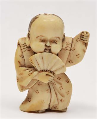 Lot 98 - A JAPANESE NETSUKE carved as a figure of Fukusuke standing in a dance pose while holding an open fan