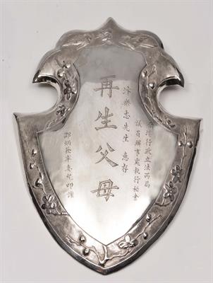 Lot 137 - A CHINESE SILVER SHIELD SHAPED PLAQUE with inscription within a border of birds and blossom