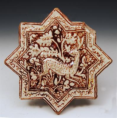 Lot 550 - AN ISLAMIC STAR SHAPED TILE with monochrome stag and foliate panel within a border of Islamic script