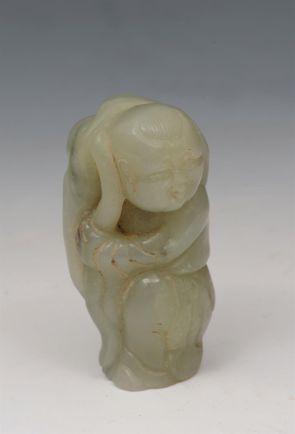 Lot 628 - A CHINESE JADE FIGURE set against and carrying a lotus leaf