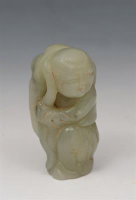 Lot 628 - A CHINESE JADE FIGURE set against and carrying a lotus leaf