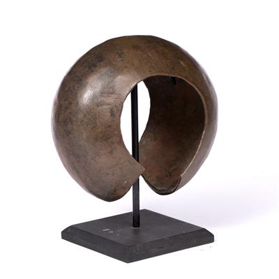 Lot 301 - AN AFRICAN BRONZE SPOT HAMMERED NECK RING of crescent shape on stand