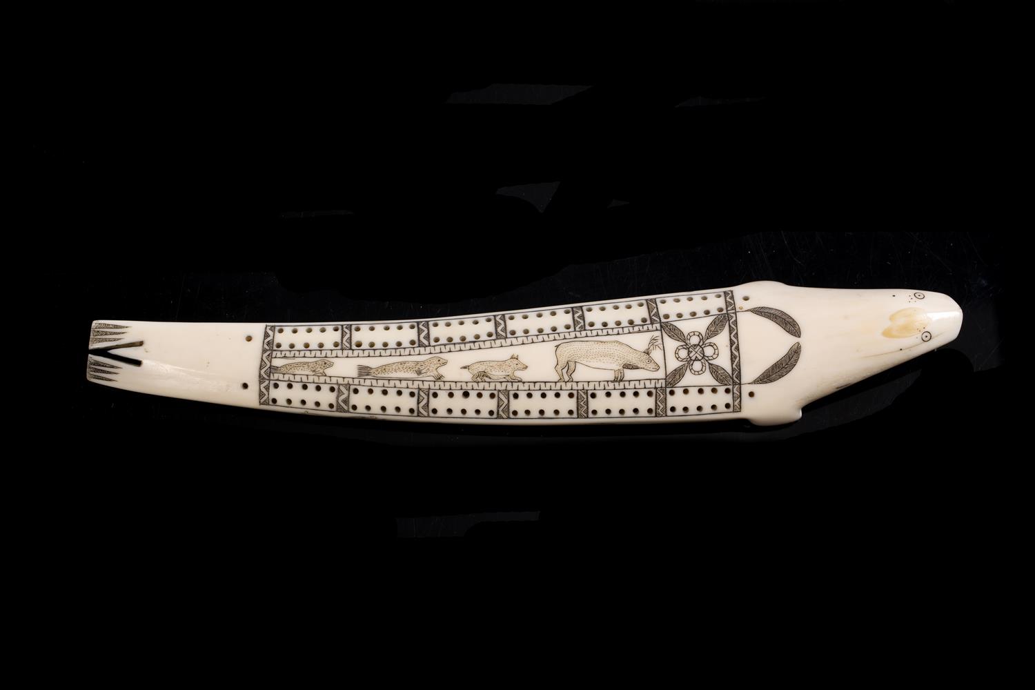 Lot 392 - AN INUIT CARVED WALRUS TUSK CRIBBAGE BOARD modelled as a seal with scrimshaw decoration