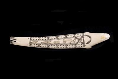 Lot 392 - AN INUIT CARVED WALRUS TUSK CRIBBAGE BOARD modelled as a seal with scrimshaw decoration