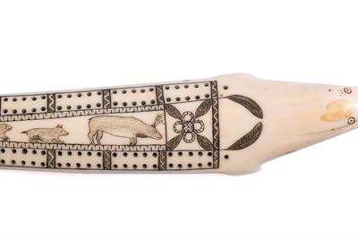 Lot 392 - AN INUIT CARVED WALRUS TUSK CRIBBAGE BOARD modelled as a seal with scrimshaw decoration