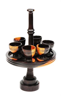 Lot 476 - A TREEN LIGNUM VITAE EGG CUP STAND with turned handle and six cups on a circular base
