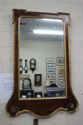 Lot 501 - AN 18TH CENTURY STYLE WALNUT VENEERED AND GILTWOOD HANGING WALL MIRROR with rosette scroll pediment