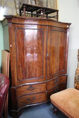 Lot 679 - A GEORGE III SERPENTINE FRONTED MAHOGANY LINEN PRESS with shaped panelled doors and canted corners