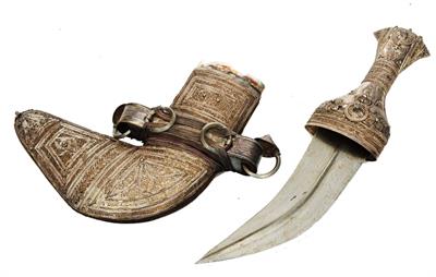 Lot 409 - AN OMANI SILVER COLOURED METAL KHANJAR OR CEREMONIAL DAGGER with finely embossed decoration