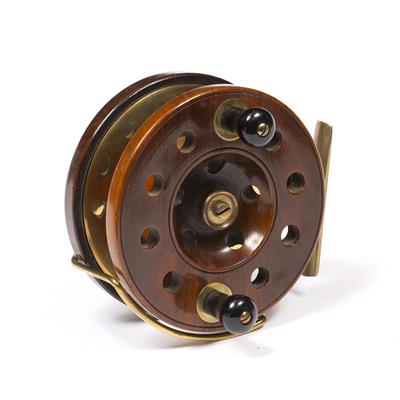 Lot 89 - A WALNUT AND BRASS MOUNTED FISHING REEL with pierced side and ebonised handles