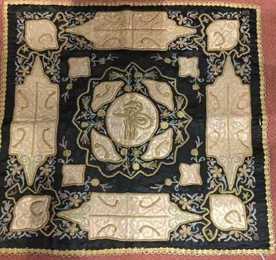 Lot 372 - A MIDDLE EASTERN EMBOSSED BLACK SILK TABLE COVER decorated on shaped panels with gold wire and