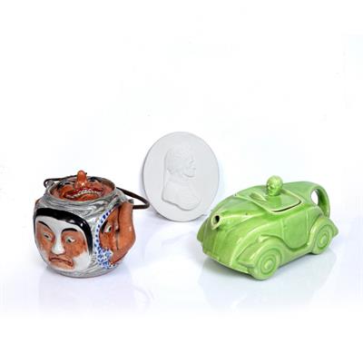 Lot 171 - A GREEN POTTERY NOVELTY TEAPOT in the form of a racing car with driver
