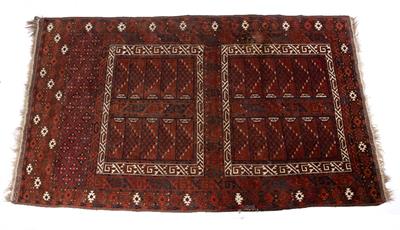 Lot 215 - A TURKOMAN WINE GROUND RUG with a central framed hooked motif within a geometric and pine cone