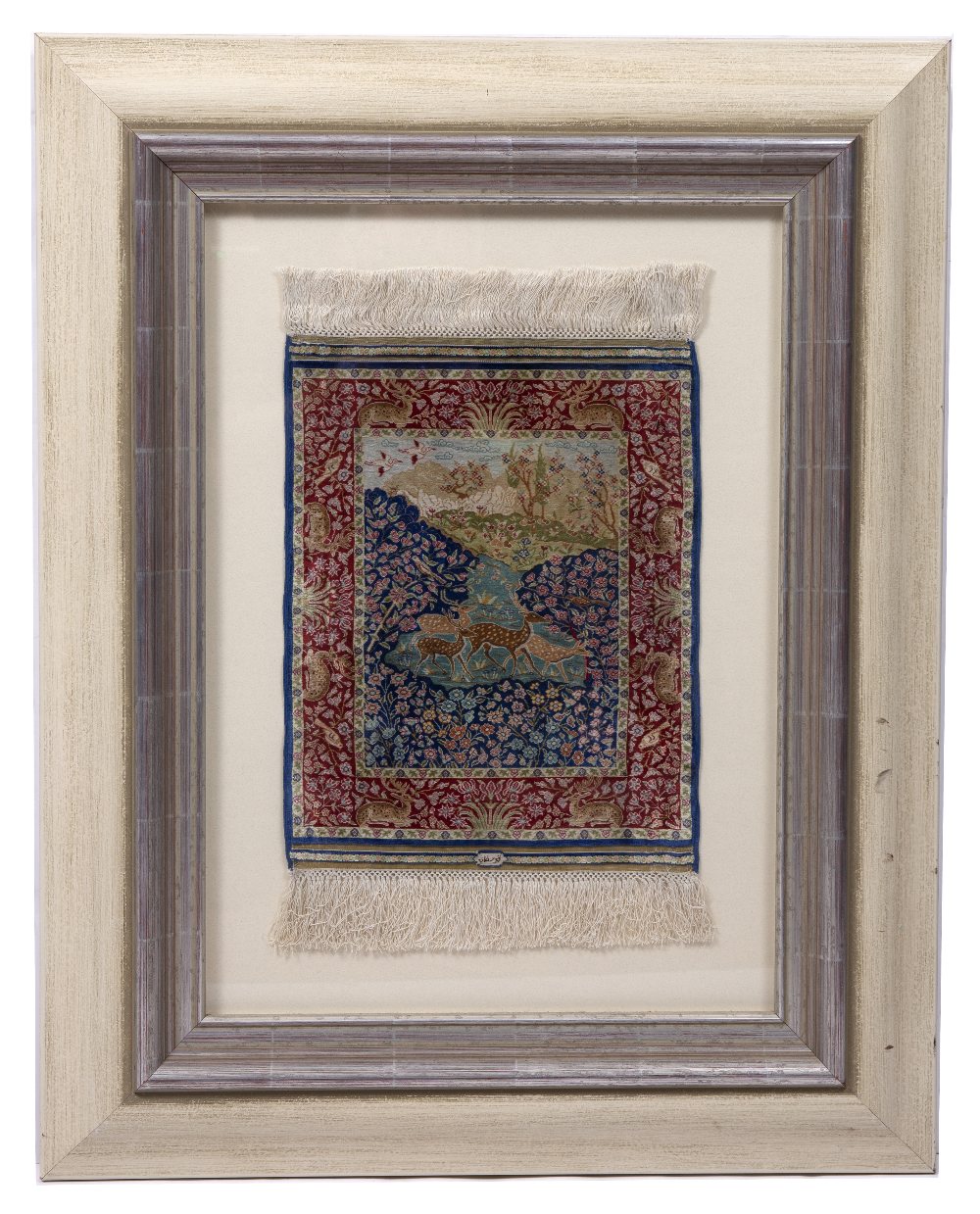 Lot 218 - A PERSIAN MINIATURE SILK RUG woven with deer in a landscape pattern in colours within a red border