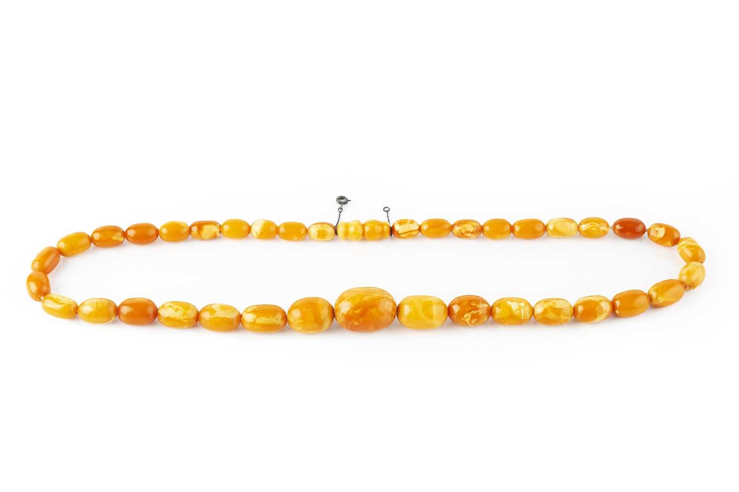 Lot 66 - An amber bead necklace, comprising a single...