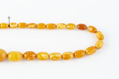 Lot 66 - An amber bead necklace, comprising a single...