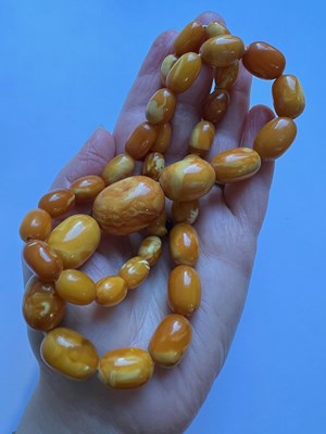 Lot 66 - An amber bead necklace, comprising a single...