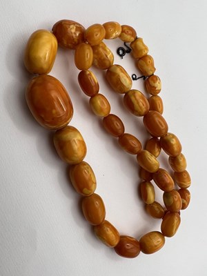 Lot 66 - An amber bead necklace, comprising a single...
