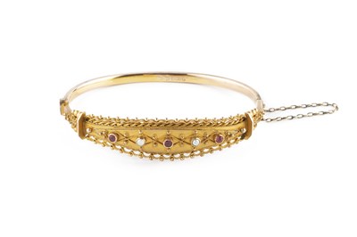 Lot 40 - An Edwardian gem set bangle, of hinged oval...