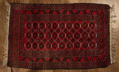 Lot 116 - Red ground wool rug with geometric designs and...