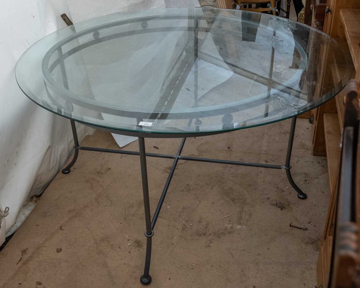 Lot 243 - A circular dining table with a glass top on a...