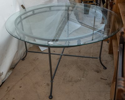 Lot 243 - A circular dining table with a glass top on a...