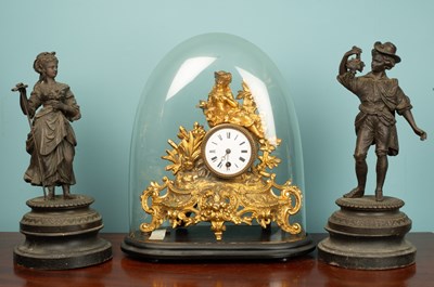 Lot 3 - A gilded spelter mantle timepiece under a...