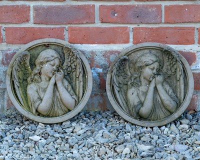 Lot 1144 - A pair of weathered cast stone roundels of winged angels