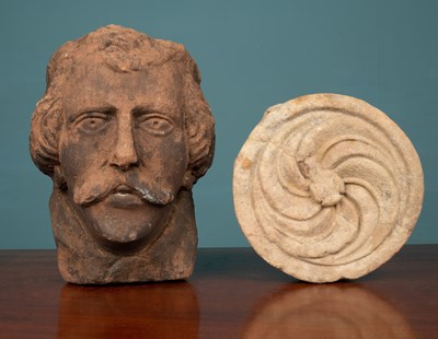 Lot 1109 - A carved sandstone head from Cockermouth, and a round carved stone element