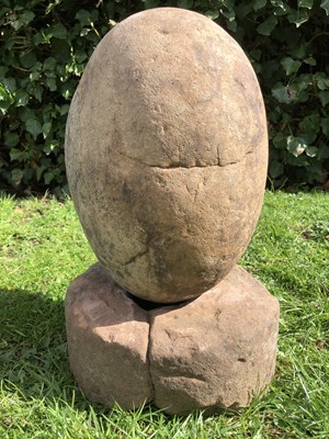 Lot 1086 - An ovoid stone sculpture on a rounded sandstone base