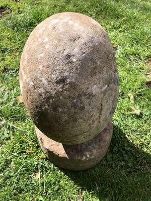 Lot 1086 - An ovoid stone sculpture on a rounded sandstone base