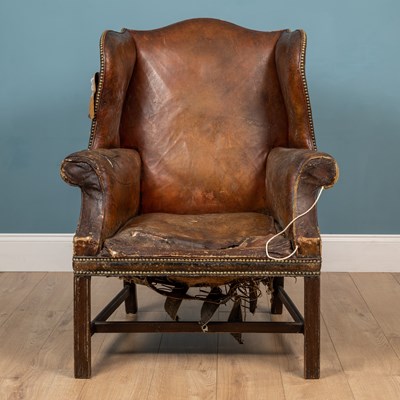 Lot 211 - A brown leather wingback armchair