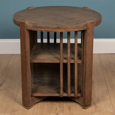Lot 4 - A Cotswold school limed oak circular occasional table with bookcase beneath
