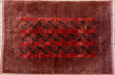 Lot 1057 - An Oriental red ground rug with twenty one motifs to the central field